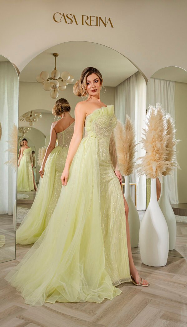 Model wearing a pastel yellow strapless draped evening gown with corset bodice, flowing tulle overlay, and thigh-high slit – Casa Reina couture.