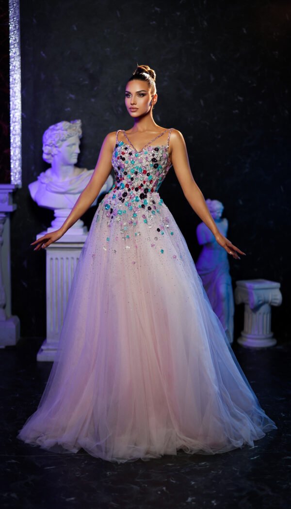 Model wearing a pastel pink evening gown with multicolored floral embellishments and layered tulle skirt – Casa Reina couture fashion.