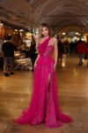 Model wearing a hot pink one-shoulder embellished evening gown with floral appliqué and thigh-high slit – Casa Reina couture fashion.