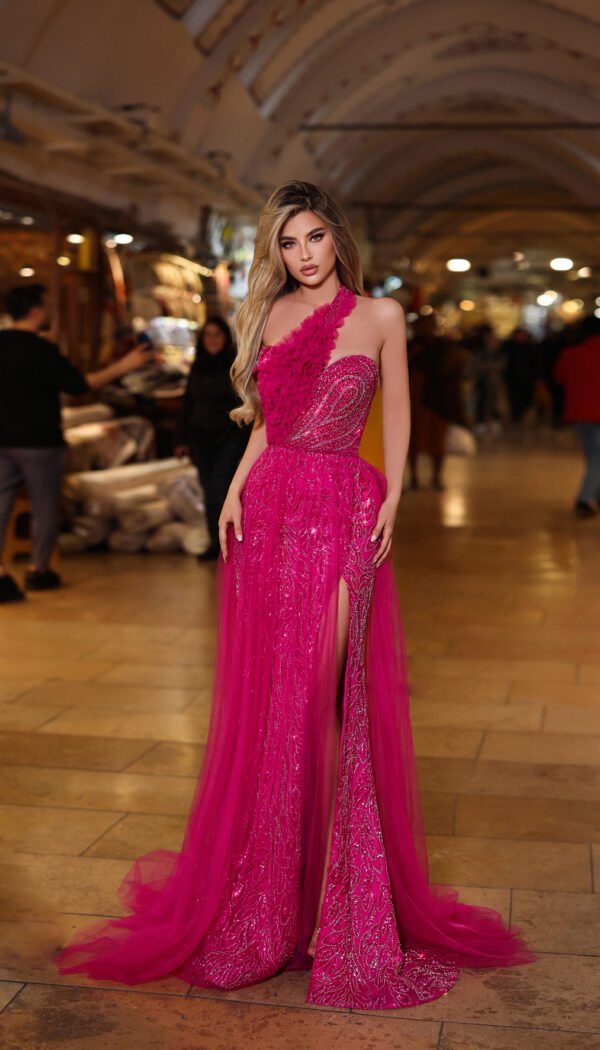 Model wearing a hot pink one-shoulder embellished evening gown with floral appliqué and thigh-high slit – Casa Reina couture fashion.