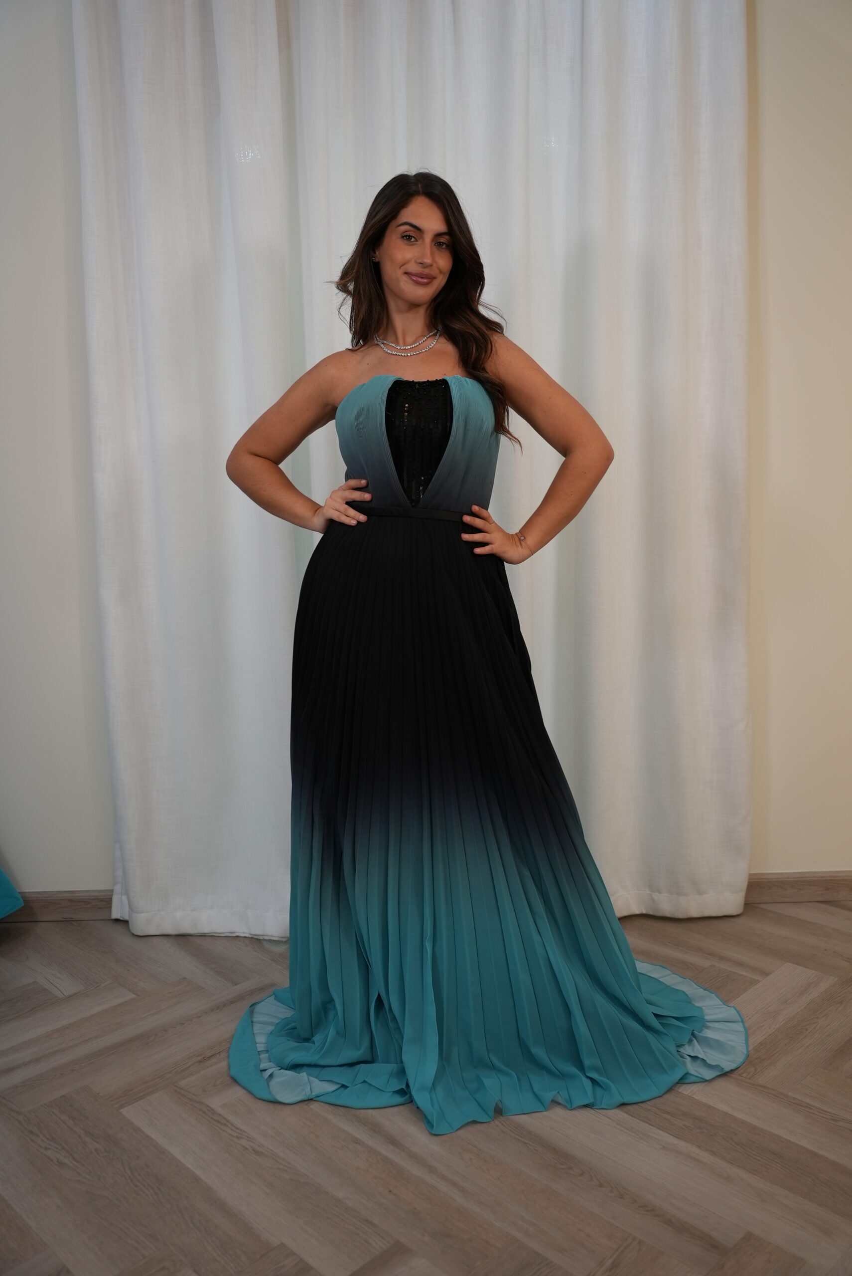 Model wearing a strapless teal-to-black ombre pleated evening gown with sequin-detailed bodice – Casa Reina Boutique