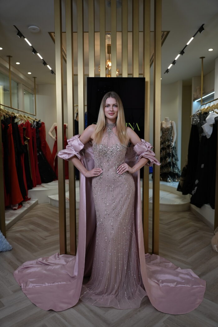 Model wearing an embellished halter evening gown with detachable satin cape in Blush Pink – Casa Reina Boutique