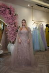 Model wearing an embroidered evening gown with 3D floral appliqué, illusion sweetheart neckline, and sheer cape sleeves in Dusty Rose – Casa Reina Boutique,