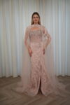 Model wearing a blush evening gown with crystal embellishments, strapless bodice, and sheer embroidered cape – Casa Reina Boutique