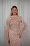 Model wearing a blush evening gown with crystal embellishments, strapless bodice, and sheer embroidered cape – Casa Reina Boutique
