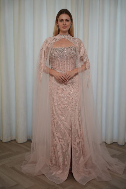 Model wearing a blush evening gown with crystal embellishments, strapless bodice, and sheer embroidered cape – Casa Reina Boutique
