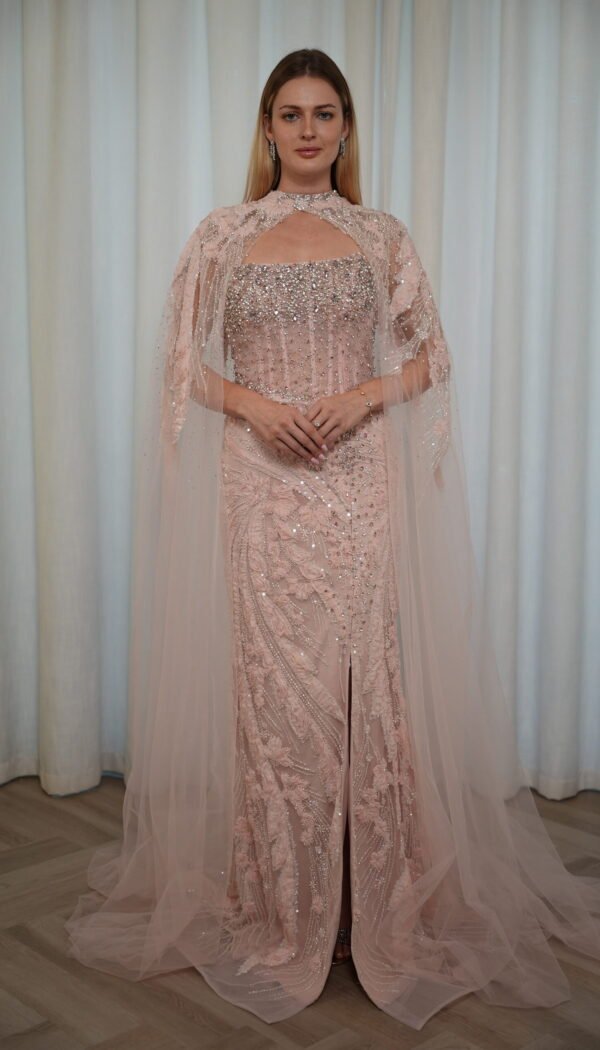 Model wearing a blush evening gown with crystal embellishments, strapless bodice, and sheer embroidered cape – Casa Reina Boutique