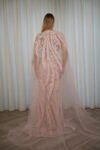 Model wearing a blush evening gown with crystal embellishments, strapless bodice, and sheer embroidered cape – Casa Reina Boutique