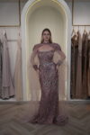 Model wearing a plum evening gown with sequins, strapless bodice, and dramatic draped crystal-beaded cape – Casa Reina Boutique