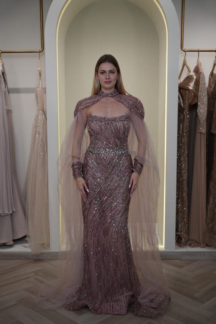 Model wearing a plum evening gown with sequins, strapless bodice, and dramatic draped crystal-beaded cape – Casa Reina Boutique