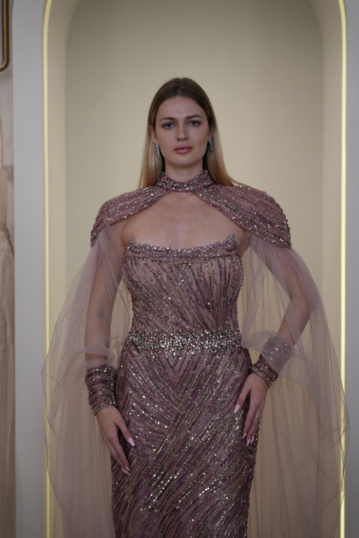 Model wearing a plum evening gown with sequins, strapless bodice, and dramatic draped crystal-beaded cape – Casa Reina Boutique