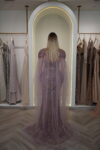 Model wearing a plum evening gown with sequins, strapless bodice, and dramatic draped crystal-beaded cape – Casa Reina Boutique