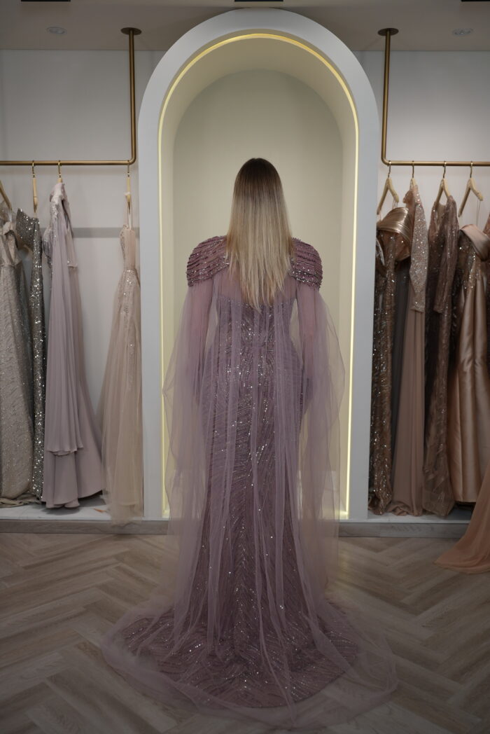 Model wearing a plum evening gown with sequins, strapless bodice, and dramatic draped crystal-beaded cape – Casa Reina Boutique