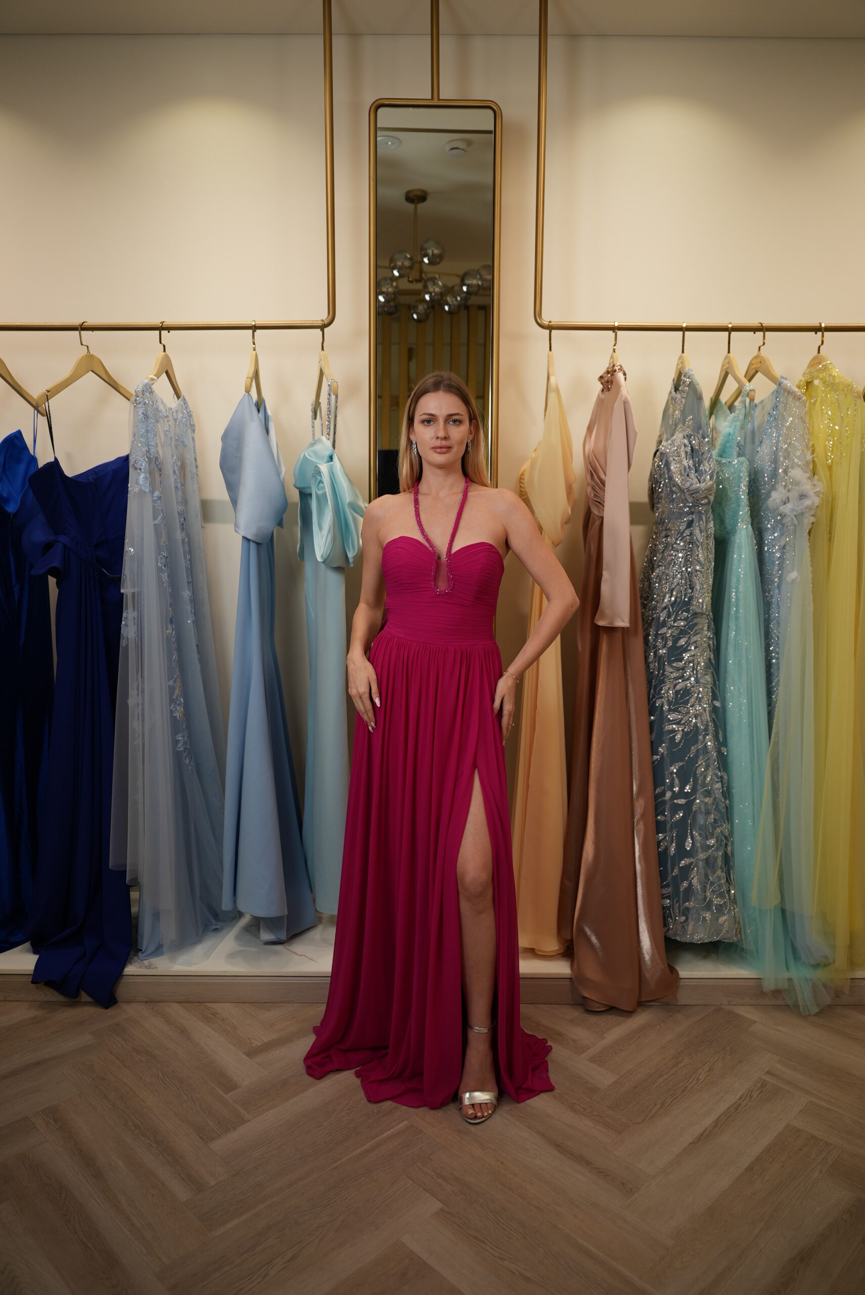 Model wearing a fuchsia halter-neck evening gown with ruched sweetheart bodice, chiffon skirt, and thigh-high slit – Casa Reina Boutique