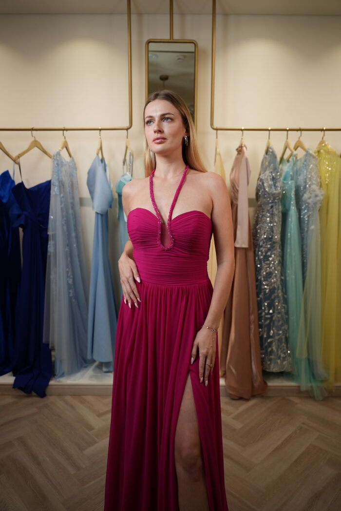 Model wearing a fuchsia halter-neck evening gown with ruched sweetheart bodice, chiffon skirt, and thigh-high slit – Casa Reina Boutique