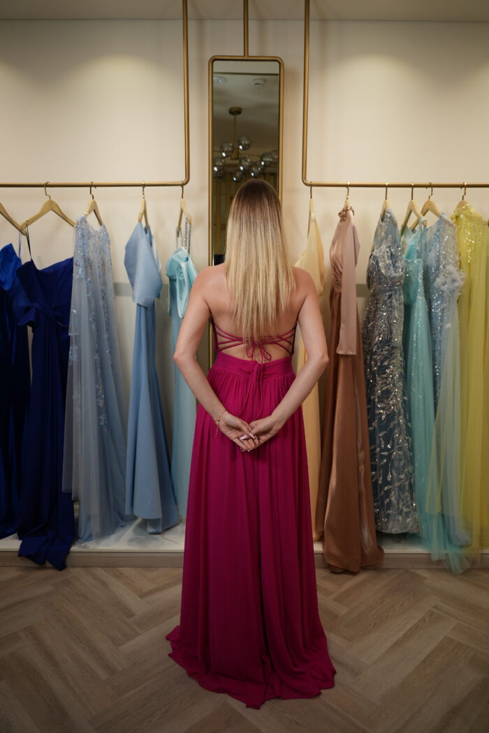 Model wearing a fuchsia halter-neck evening gown with ruched sweetheart bodice, chiffon skirt, and thigh-high slit – Casa Reina Boutique