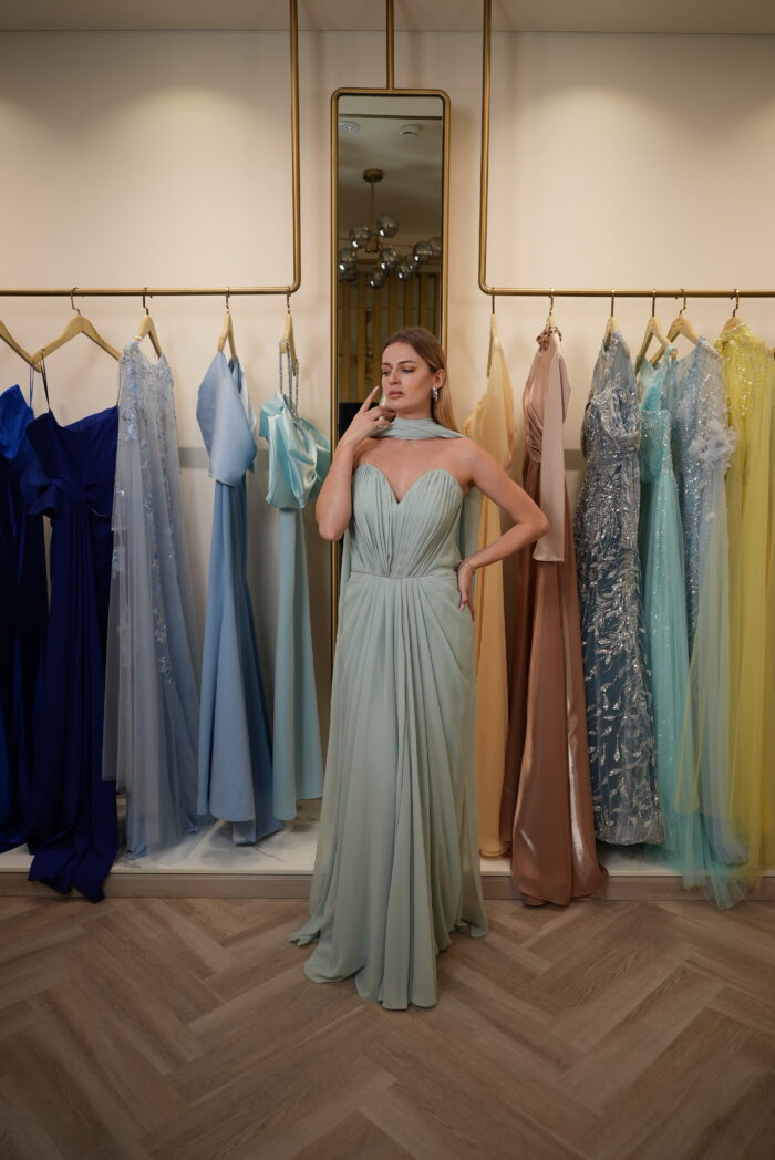 Model wearing a mint green strapless chiffon gown with sweetheart neckline, draped skirt, and detachable scarf detail – Casa Reina Boutique