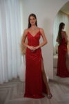 Model wearing a sequin spaghetti strap evening gown with V-neckline, ruched waist, and thigh-high slit, available in red– Casa Reina couture collection.