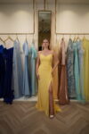 Model wearing a vibrant yellow sweetheart evening gown with ruched bodice, draped detailing, and thigh-high slit – Casa Reina Boutique