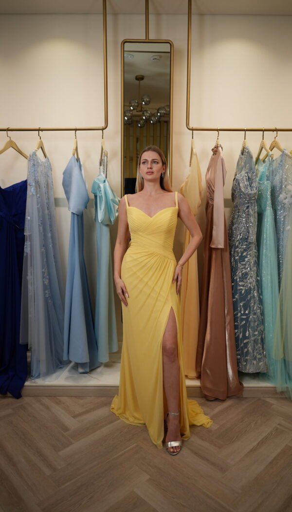 Model wearing a vibrant yellow sweetheart evening gown with ruched bodice, draped detailing, and thigh-high slit – Casa Reina Boutique