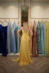 Model wearing a vibrant yellow sweetheart evening gown with ruched bodice, draped detailing, and thigh-high slit – Casa Reina Boutique