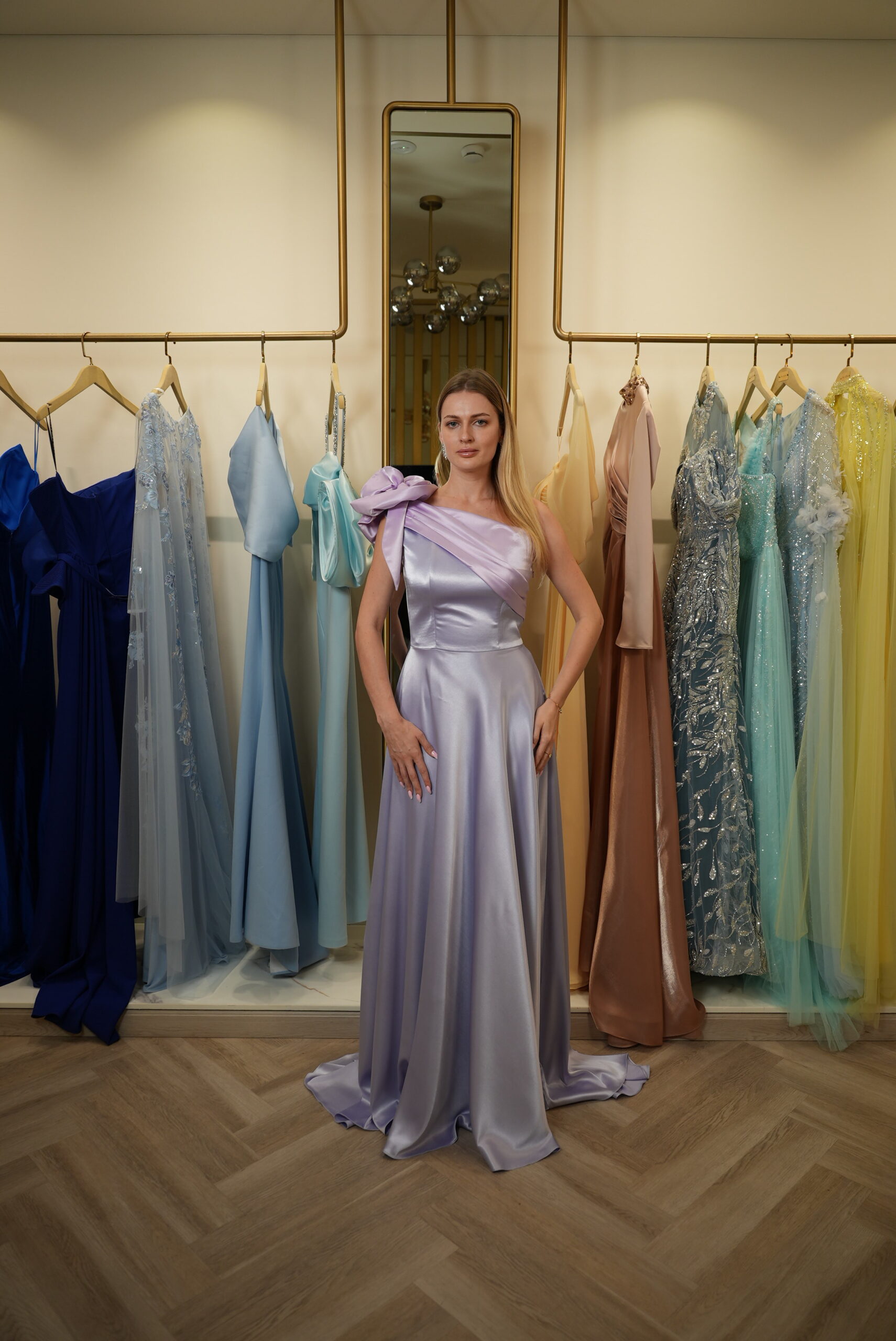 Model wearing a lilac satin one-shoulder evening gown with oversized draped bow detail – Casa Reina Boutique
