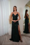 vModel wearing a sequin spaghetti strap evening gown with V-neckline, ruched waist, and thigh-high slit, available emerald green – Casa Reina couture collection.