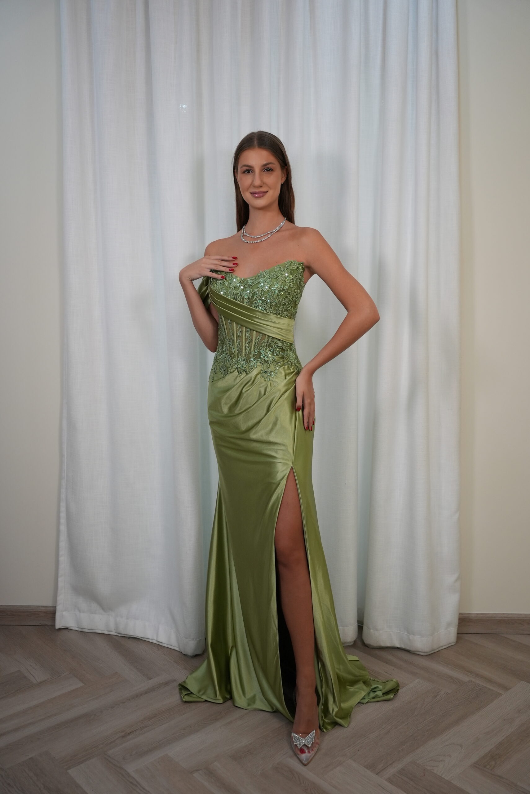 Model wearing an embellished strapless satin evening gown with embroidered corset bodice and thigh-high slit, available in emerald green – Casa Reina couture collection.