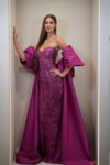 Model wearing a magenta strapless sequin evening gown with sweetheart neckline, detachable puff sleeves, and flowing cape – Casa Reina couture collection.