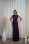 Model wearing a sleeveless evening gown with bateau neckline, draped waist, side ruffle, and thigh-high slit, available in plum – Casa Reina couture collection.