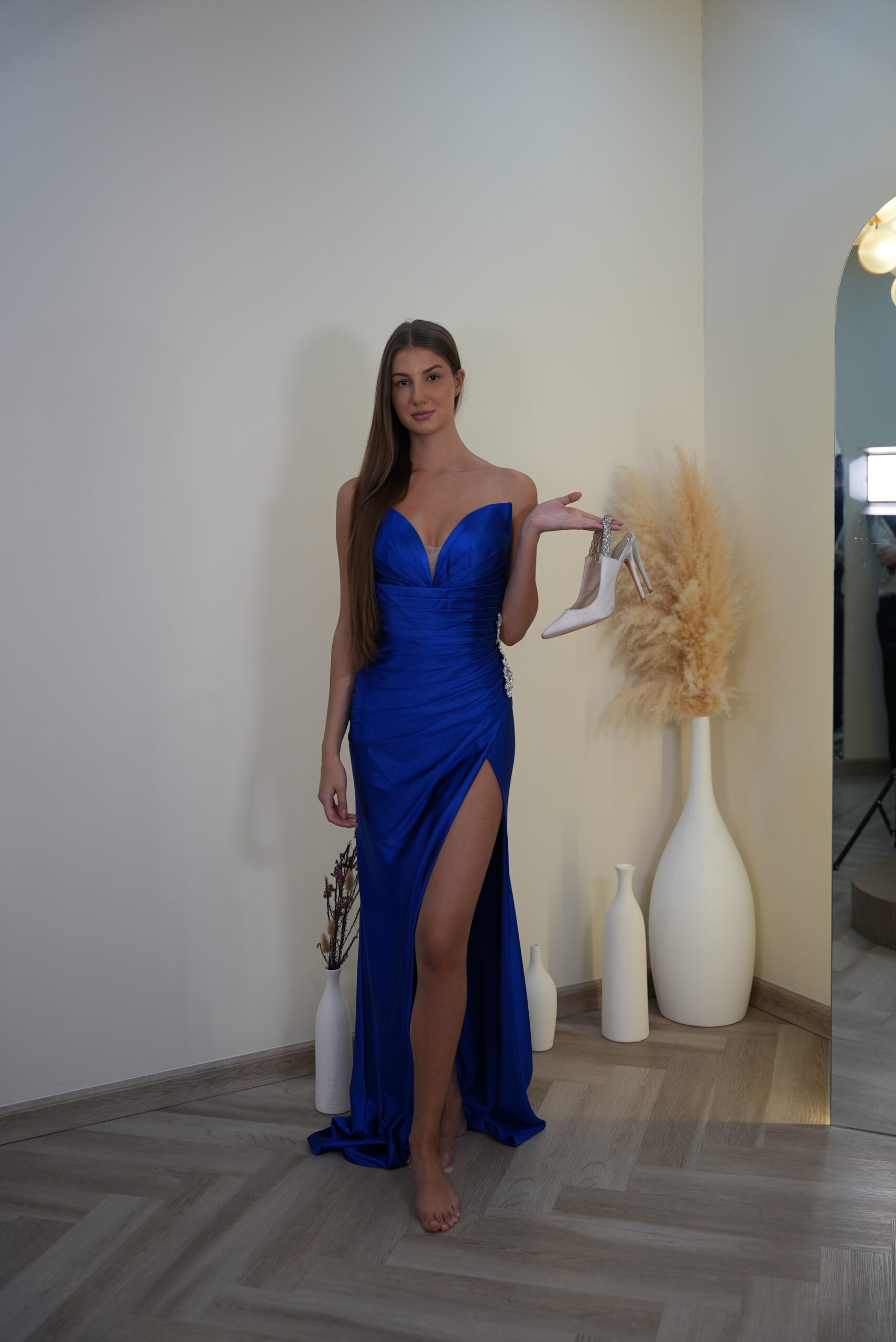 Model wearing a royal blue satin gown with sweetheart neckline, crystal hip embellishment, and thigh-high slit – Casa Reina Boutique