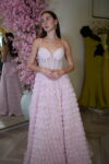 Model wearing a pink corset evening gown with embellished bodice and 3D rosette skirt featuring a thigh-high slit – Casa Reina couture collection.