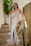 Model wearing a champagne one-shoulder evening gown with crystal embellishments, thigh-high slit, and draped shawl – Casa Reina Boutique