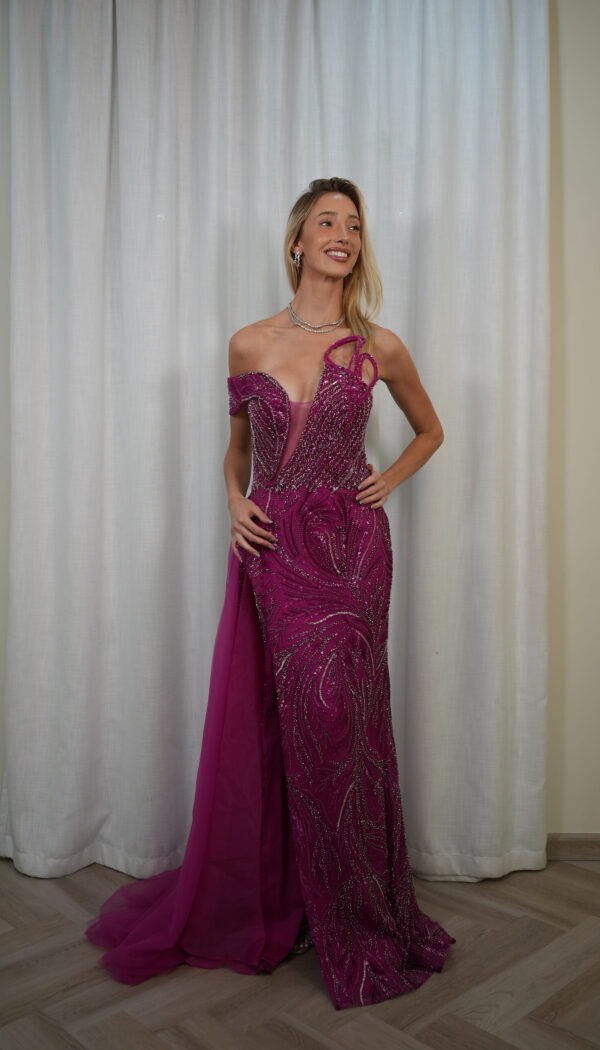 Model wearing a fuchsia evening gown with beaded illusion bodice, asymmetrical off-shoulder strap, and floor-length skirt with soft train – Casa Reina Boutique
