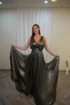 Model wearing a metallic gunmetal pleated evening gown with a deep V-neckline and flowing skirt – Casa Reina couture.