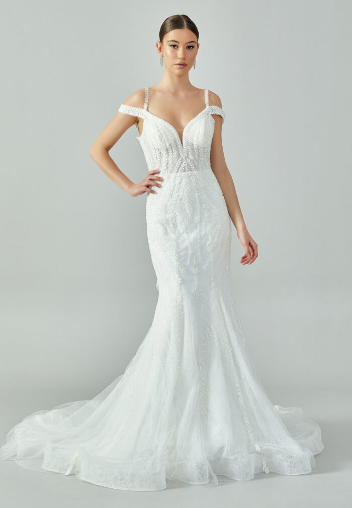 Bride wearing a beaded mermaid gown with illusion V-neckline and off-shoulder straps from Casa Reina Bridal Collection