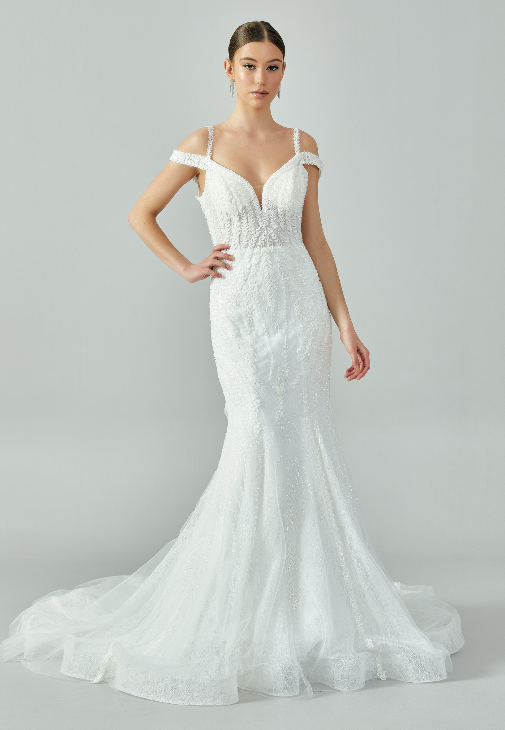 Bride wearing a beaded mermaid gown with illusion V-neckline and off-shoulder straps from Casa Reina Bridal Collection