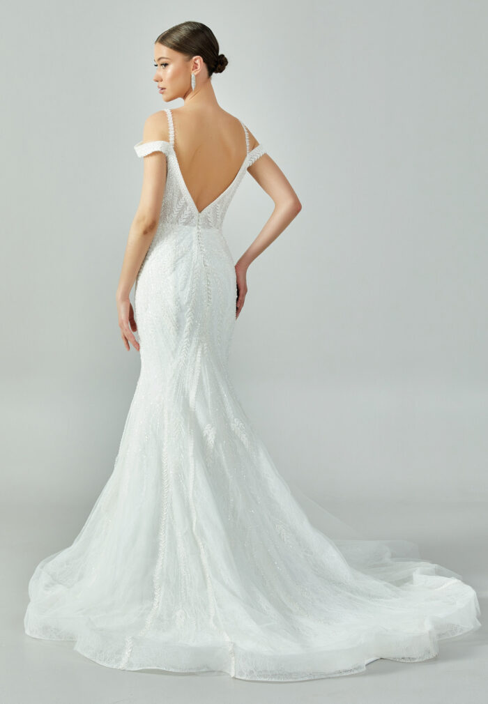 Bride wearing a beaded mermaid gown with illusion V-neckline and off-shoulder straps from Casa Reina Bridal Collection