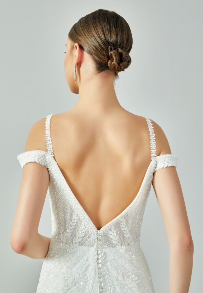 Bride wearing a beaded mermaid gown with illusion V-neckline and off-shoulder straps from Casa Reina Bridal Collection