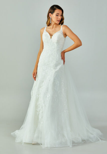 Bride wearing a lace-embroidered fit and flare gown with illusion straps and chapel-length tulle train from Casa Reina Bridal Collection