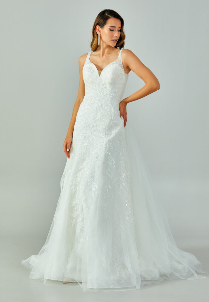 Bride wearing a lace-embroidered fit and flare gown with illusion straps and chapel-length tulle train from Casa Reina Bridal Collection