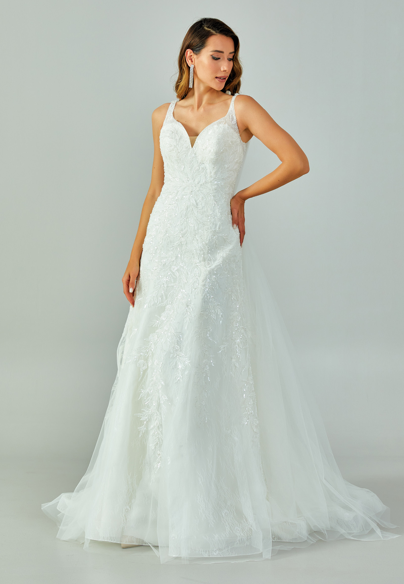 Bride wearing a lace-embroidered fit and flare gown with illusion straps and chapel-length tulle train from Casa Reina Bridal Collection