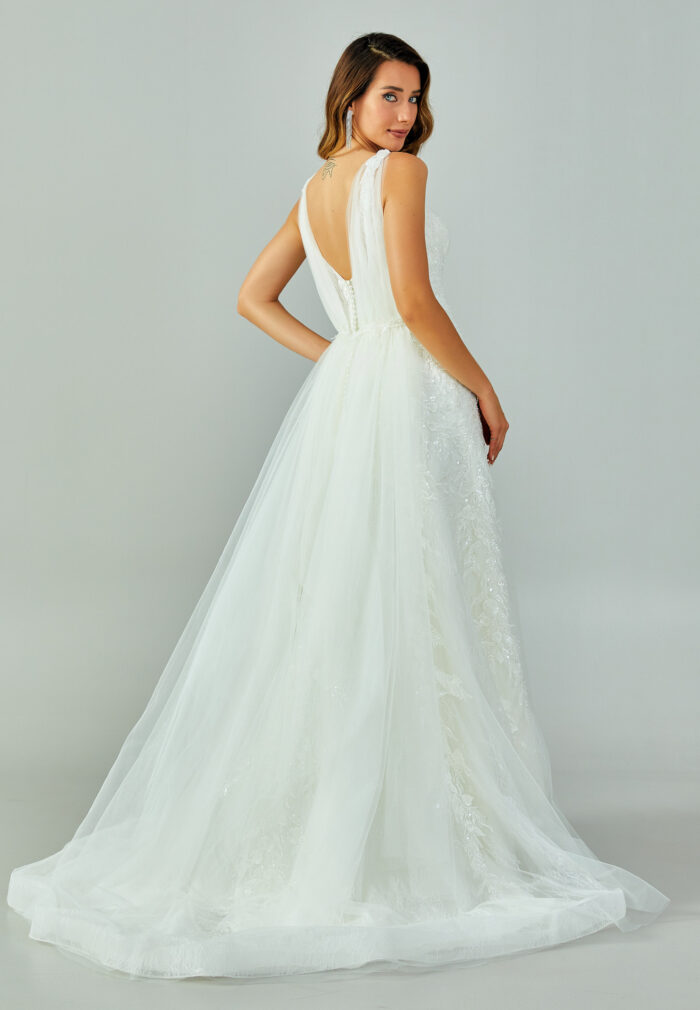 Bride wearing a lace-embroidered fit and flare gown with illusion straps and chapel-length tulle train from Casa Reina Bridal Collection