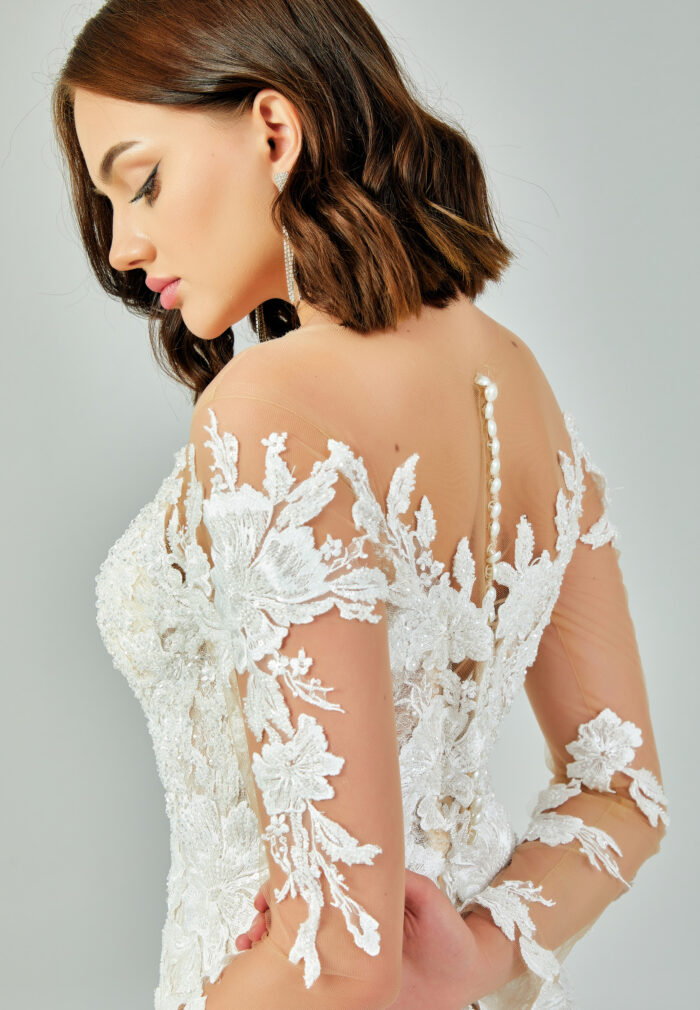 Bride wearing a regal long-sleeved ball gown with beaded embroidered bodice and illusion neckline from Casa Reina Bridal Collection