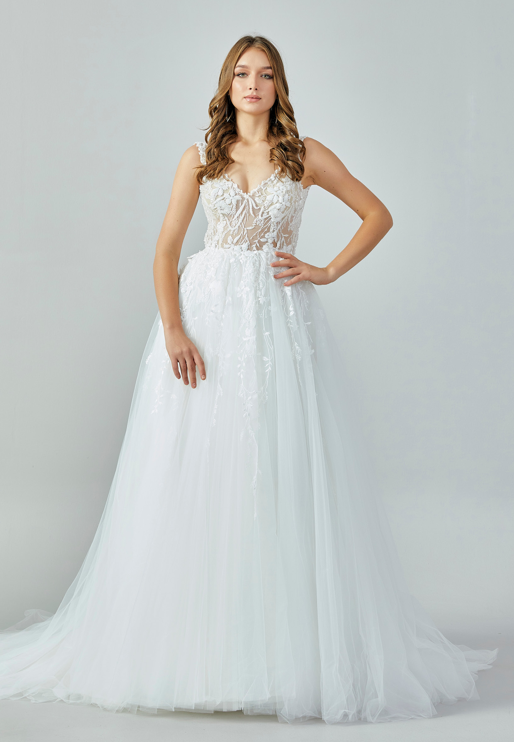 Bride wearing an ivory illusion lace and tulle A-line gown with deep V neckline and chapel train from Casa Reina Bridal Collection