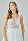 Bride wearing an ivory illusion lace and tulle A-line gown with deep V neckline and chapel train from Casa Reina Bridal Collection