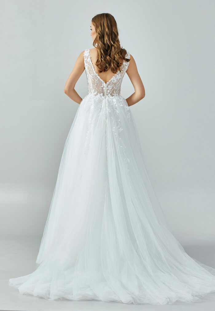 Bride wearing an ivory illusion lace and tulle A-line gown with deep V neckline and chapel train from Casa Reina Bridal Collection
