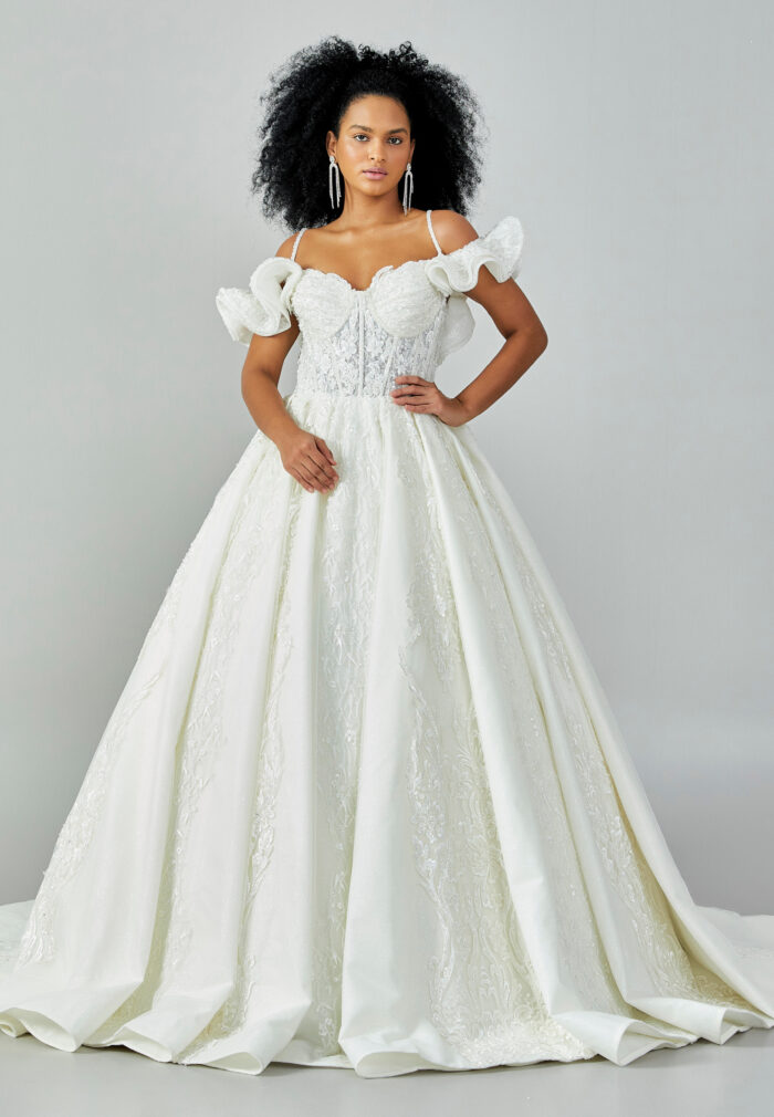 Bride wearing a ruffled off-shoulder ball gown with beaded corset bodice and embroidered jacquard skirt from Casa Reina Bridal Collection