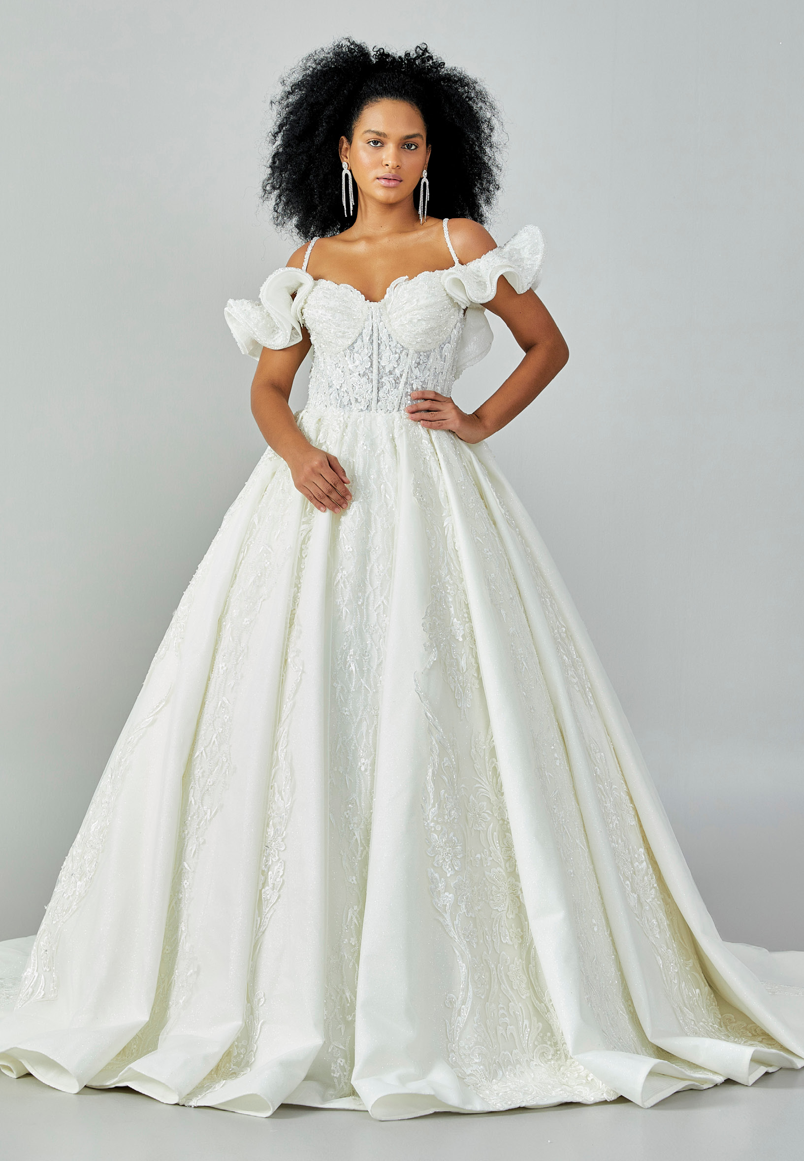 Bride wearing a ruffled off-shoulder ball gown with beaded corset bodice and embroidered jacquard skirt from Casa Reina Bridal Collection
