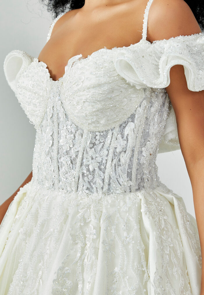 Bride wearing a ruffled off-shoulder ball gown with beaded corset bodice and embroidered jacquard skirt from Casa Reina Bridal Collection